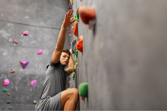 Indoor Bouldern Mann bouldert in der Halle an einer Boulderwand